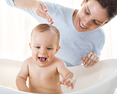 Mamá bañando a su bebé en una bañera